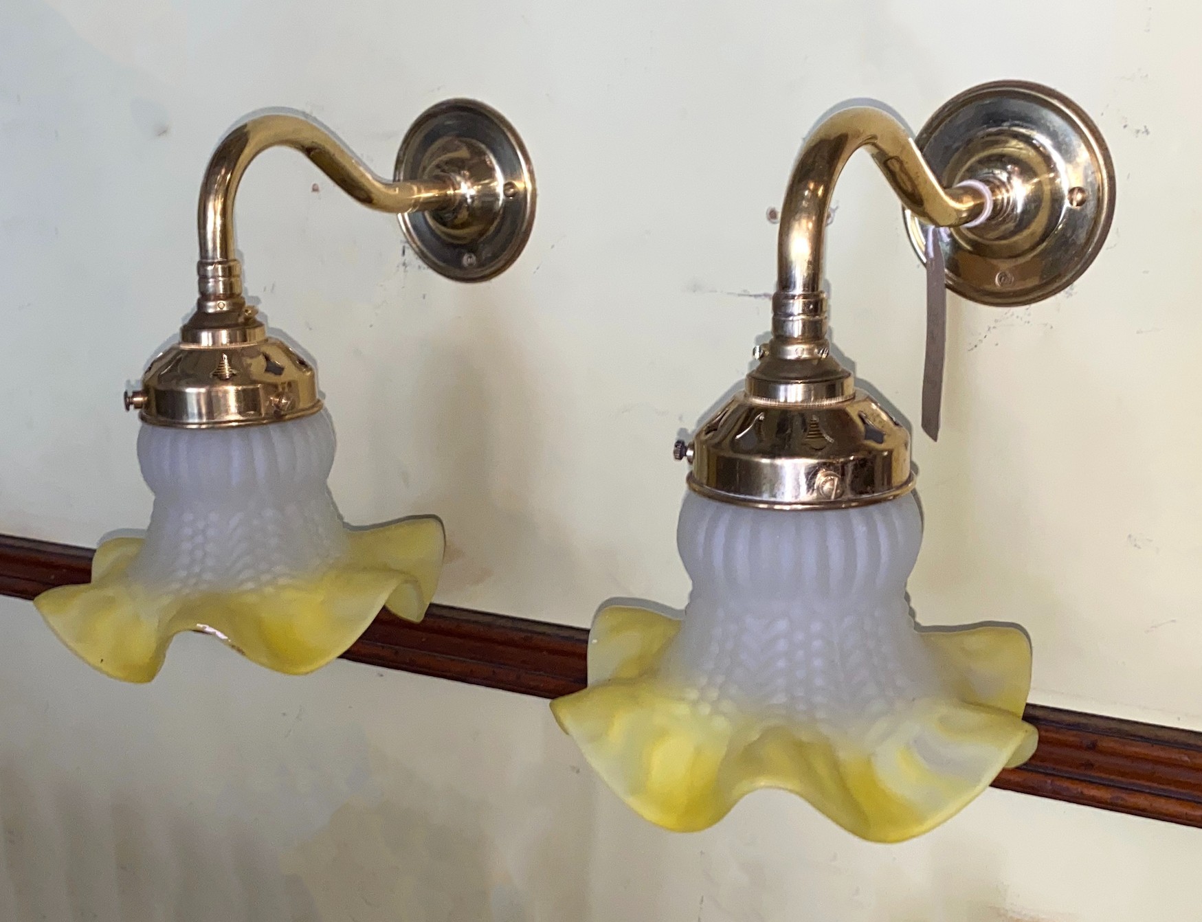 A pair of 1930s French lacquered brass wall lights with yellow tinted quilted and frosted glass shades, height 19cm